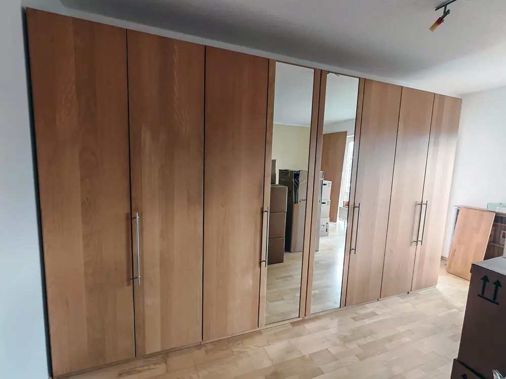 Ein fertig aufgebauter Schlafzimemrschrank mit Holzfront und Spiegeltüren