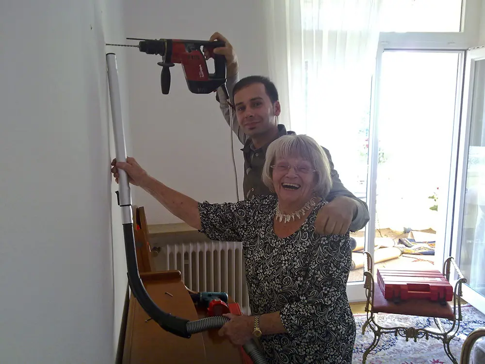 Herr Pir und eine Seniorin beim Bohren der Wand