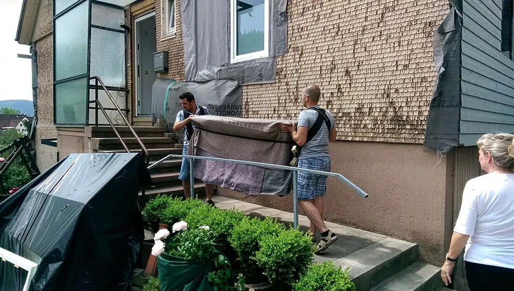 Mitarbeiter transportieren vorsichtig ein antikes Möbelstück per Hand