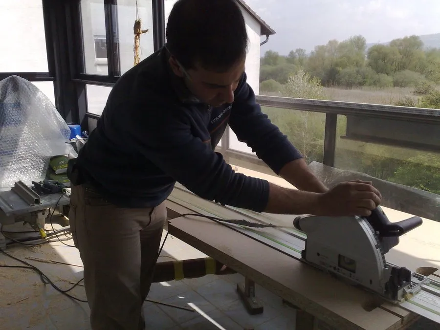 Ein Mitarbeiter sägt zur Anpassung der Möbel ein Brett zurecht